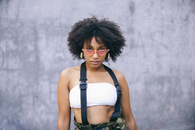 Portrait of woman with frizzy hair standing against wall