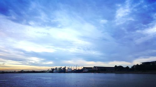 View of buildings by sea against cloudy sky