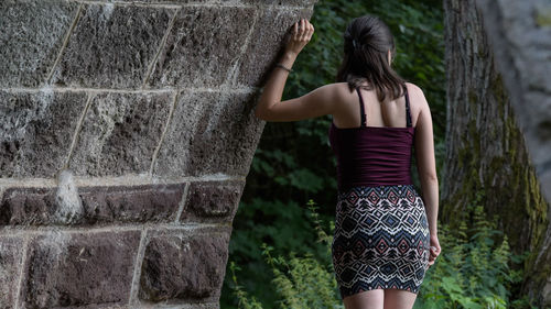 Rear view of young woman standing against tree