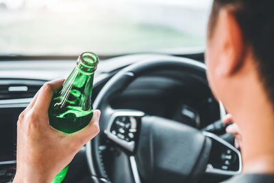 Midsection of man holding bottle in car