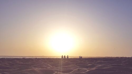 Silhouette people on land against sky during sunset