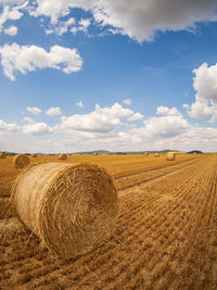 Hay bales on field against sky