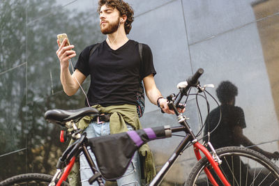 Young man with bicycle on road in city