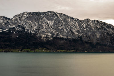 Scenic view of sea by mountain against sky