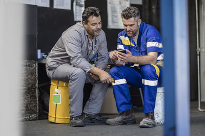 Two workers having a break looking at cell phone