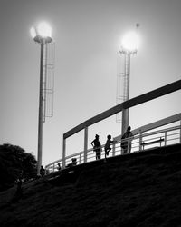 Silhouette of people standing atop stadium at night