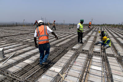 Rear view of people working against sky