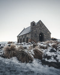 Old building on field against clear sky during winter