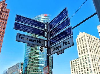 Low angle view of road signs against buildings in city