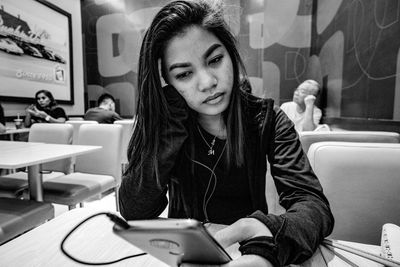 Young woman looking away while sitting on table