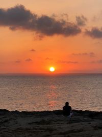 Silhouette people looking at sea against sky during sunset