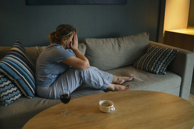 Young woman sitting on sofa at home