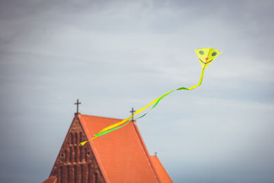 Low angle view of kite flying by church in city