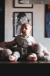 Cute baby boy sitting on toy at home