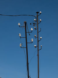 Low angle view of telephone pole against clear blue sky