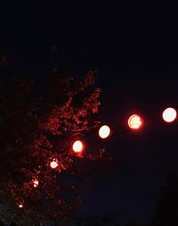 Low angle view of illuminated lights against sky at night