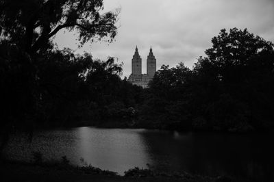 View of building by river against cloudy sky