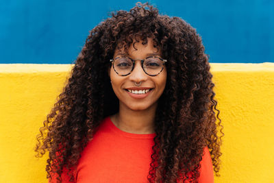 Portrait of smiling young woman against wall