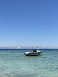 Sailboat on sea against clear blue sky