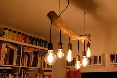 Low angle view of illuminated light bulb hanging at home