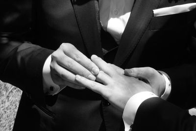 Midsection of bride putting ring in hand of bride