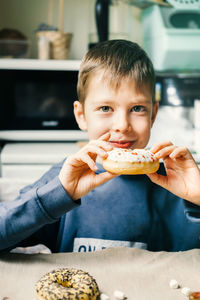 Funny boy with donut. child is having fun with doughnut. tasty food for kids. happy time at home 