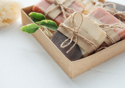 Assorted handmade soap bars and green leaves in box on straw
