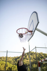 Low angle view of man playing basketball against clear sky
