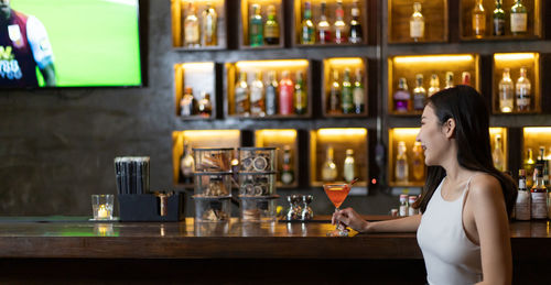 Full length of woman drinking glass at bar