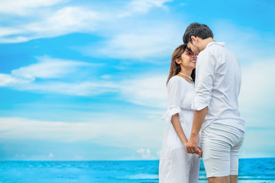 Young couple standing in sea against sky