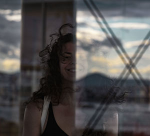 Portrait of young woman looking through window