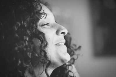 Close-up side view of smiling young woman at home