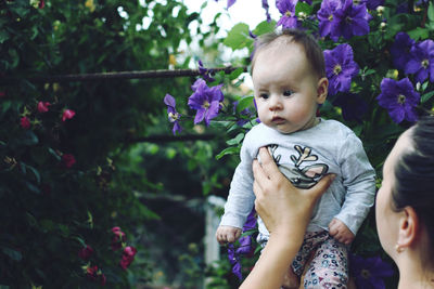 Cropped image of mother holding daughter by purple flowers