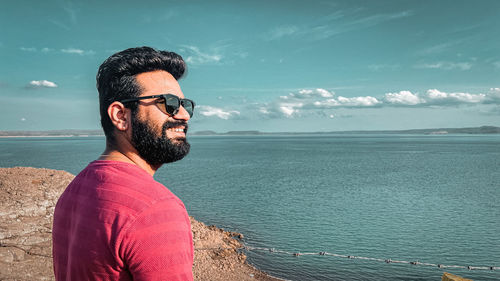 Portrait of young man looking at sea against sky