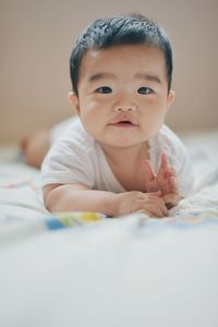 Portrait of cute baby boy on bed at home