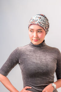 Young woman looking away against gray background