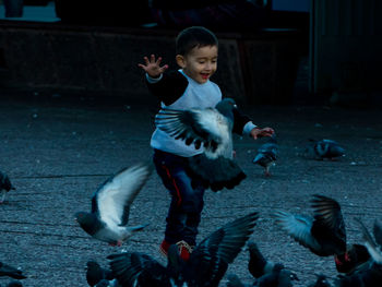 Cheerful boy running by birds on footpath