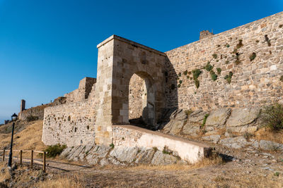 Low angle view of old ruins against clear blue sky