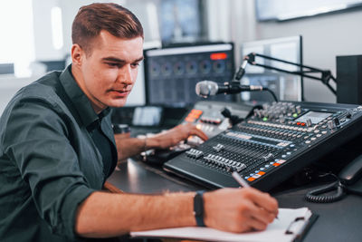 Document with scenario. young man is indoors in the radio studio is busy by broadcast.