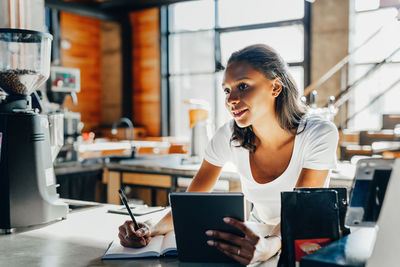 Young woman using phone while sitting on table