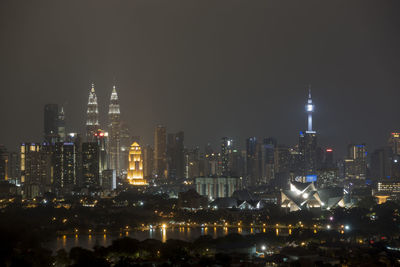 Illuminated buildings in city against sky at night