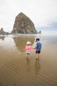 Brother and sister holding hands while at the beach.