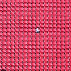 Man standing amidst red chairs at stadium
