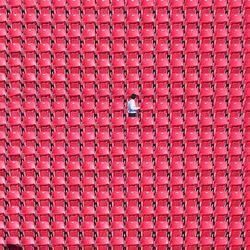 Man standing amidst red chairs at stadium