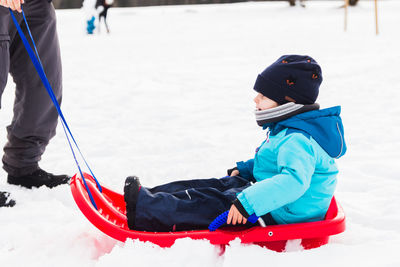 Rear view of boys on snow covered landscape during winter