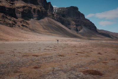 Distant view of person standing against rock formations