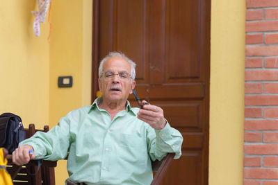 Man holding camera while standing against brick wall