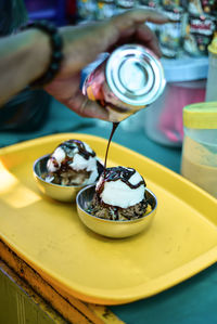 Close-up of hand holding ice cream on table