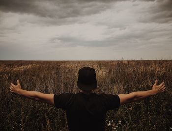 Rear view of man standing on field against sky