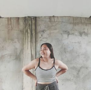 Young woman standing against wall